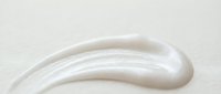White cosmetic cream swirl on beige background for skincare and beauty product advertising.