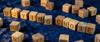 Wooden letter blocks spelling "BUYING CHOICE" arranged on a textured blue surface with scattered cubes, representing consumer decisions and purchasing options for retail and marketing materials.