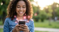 Happy young African American woman using smartphone with floating heart icons in park during golden hour for social media dating apps and digital communication.