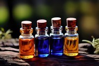 Small glass bottles with colorful essential oils and cork stoppers arranged on rustic wood, showcasing aromatherapy ingredients for wellness and spa treatments.