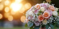 Romantic wedding bouquet with peach and pink roses, white baby's breath against golden sunset bokeh background. Fresh floral arrangement for bridal ceremonies.