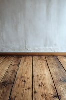 Empty room interior with rustic wooden floorboards and white plastered wall, showing natural wood grain texture and baseboard trim. Perfect for interior design projects.