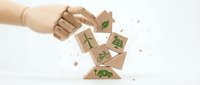 Wooden hand reaching for falling eco-friendly cubes with green sustainability symbols including recycling, trees, and renewable energy icons.