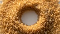 Golden brown sugar granules arranged in circular formation with hollow center opening, suitable for food and culinary design projects.