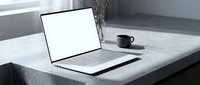 Modern laptop with blank white screen on marble desk next to coffee cup in minimalist office workspace for business presentations and mockup designs.