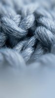 Closeup of twisted gray and white textile fibers or yarn strands intertwined together, showcasing detailed texture and depth for fabric, textile design, or material backgrounds.