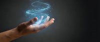 Human hand holding glowing blue holographic planet Earth with orbital rings and particles floating above palm against dark background for technology concepts.