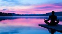 Silhouette of person meditating on wooden pier at sunset, purple and pink sky reflects in calm lake water surrounded by mountain landscape.