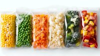 Frozen vegetables in transparent plastic bags arranged in row showing variety of colorful produce including corn, peas, carrots, cauliflower, broccoli and peppers.