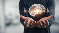 Professional man holding glowing brain with heartbeat pulse waves above open palms representing mental health, neuroscience and cognitive wellness concepts.