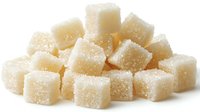 White sugar cubes scattered in pile on white background, crystalline granulated sweetener close up macro photography showing texture and sparkle detail.