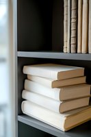 Stack of white hardcover books on gray bookshelf with soft natural lighting, creating minimalist composition for reading, education and literature concepts.