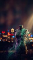 Mannequin torso with glowing neon green and purple particles dissolving into light against blurred city bokeh background. Fashion design concept.