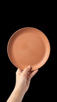 Terracotta ceramic plate held in hand, isolated on transparent background. Ready for design use on product mockups, kitchen decor graphics, tableware catalogs, print-on-demand merchandise, and digital design projects.