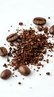 Ground coffee beans and whole roasted beans scattered on white background for brewing and cafe concepts.