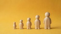 Five wooden figurines arranged by increasing height on a yellow background, symbolizing human growth, development stages, and life progression.
