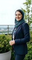 Middle Eastern woman in professional navy blazer and hijab smiling on modern rooftop terrace with green plants and city views, suitable for corporate, business, and diversity stock imagery.