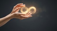 Female hands holding a glowing golden infinity symbol on dark background, representing endless possibilities, eternity, and limitless potential.