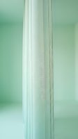 Sheer white curtain fabric hanging in soft natural light against mint green wall, suitable for interior design and home decor projects.