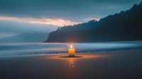 Glowing candle on misty beach at dusk creates atmospheric scene with dramatic coastal cliffs and moody ocean waves, offering peaceful meditation ambiance.
