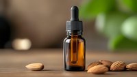 Amber glass dropper bottle with almond oil on wooden surface surrounded by fresh almonds for natural skincare and aromatherapy treatments.