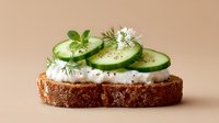 Fresh cucumber slices with herbs and cream cheese on artisan bread slice, healthy breakfast or snack concept for organic food photography.