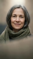 Mature woman with gray hair wearing a knit scarf, displaying a calm, confident expression against a neutral background for portrait and lifestyle use.