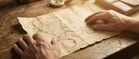 Close-up of mature hands examining vintage map on wooden table, suggesting travel planning, exploration, or historical research for adventure and navigation themes.