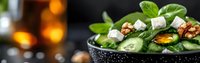 Fresh spinach salad with feta cheese, walnuts and herbs in speckled bowl. Healthy green leafy vegetables meal with nuts and dairy for restaurant menu.