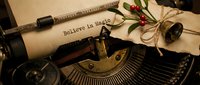 Vintage typewriter with aged paper reading Believe in Magic, decorated with holly berries and a bell, evoking holiday nostalgia and festive inspiration.
