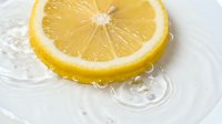 Fresh lemon slice splashing in clear water, showing vibrant yellow citrus fruit with ripples, perfect for food, beverage, and health concepts.