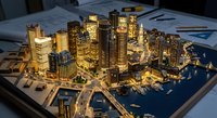 Illuminated architectural scale model of modern city skyline with skyscrapers and urban planning layout on desk with blueprints for development presentation.