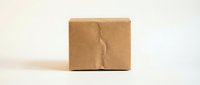 Cracked brown cardboard shipping box on white background showing damage from rough handling during delivery and transportation.