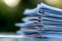 Stack of paper documents and files with selective focus on edges, creating blurred bokeh background effect for business and office workflow concepts.