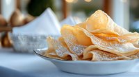 Crispy homemade potato chips dusted with salt in white bowl, shallow depth of field with soft blurred background for food photography.