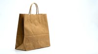 Brown kraft paper shopping bag with twisted handles isolated on white background for retail packaging and eco-friendly branding projects.