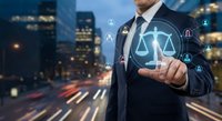 Professional businessman touching digital justice scales hologram with legal icons against modern city skyline at night for law technology concepts.