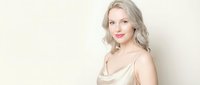 Young blonde Caucasian woman in elegant champagne silk camisole top against neutral beige background. Professional portrait for fashion and beauty content.