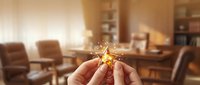 Hands holding golden star ornament in cozy living room with warm lighting and leather furniture during holiday season for festive home decoration.