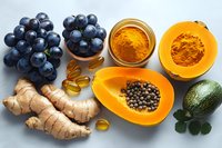 Fresh grapes, papaya, ginger root, turmeric powder and omega supplements arranged on light background, antioxidant rich foods and natural supplements for health.