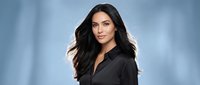 Professional young Hispanic businesswoman with long dark hair wearing black shirt against blue gradient background for corporate headshot photography.
