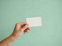 Hand holding blank white business card against mint green background for branding and marketing mockup designs.