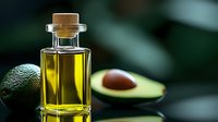 Fresh avocado oil in glass bottle with raw avocado and lime on dark background, natural organic cosmetic and cooking ingredient for healthy lifestyle.