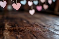 Romantic pastel heart decorations hanging over rustic wooden surface with soft blur effect creating dreamy Valentine's Day or wedding atmosphere.