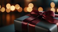 Elegant gift box with burgundy satin ribbon and bow against warm bokeh lights background for holiday celebrations and special occasions.