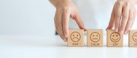 Hand selecting wooden blocks with emotion faces from sad to joy showing customer satisfaction rating and feedback concept for business evaluation.