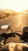 Motorcycle rider's point of view on desert highway at golden hour sunset, traveling through arid landscape with open road ahead and mirror reflection visible for travel and adventure concepts.