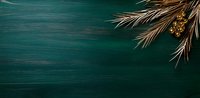 Golden Christmas decorations and dried palm leaves on dark emerald green wooden background with copy space for seasonal holiday greeting cards.
