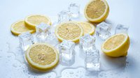 Fresh lemon slices and ice cubes on a white wet surface, showcasing a cool citrus concept for food and beverage design.