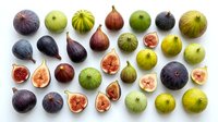 Assorted fresh figs in various stages of ripeness, whole and halved, displaying green, yellow, and deep purple varieties on white background for culinary and food styling projects.